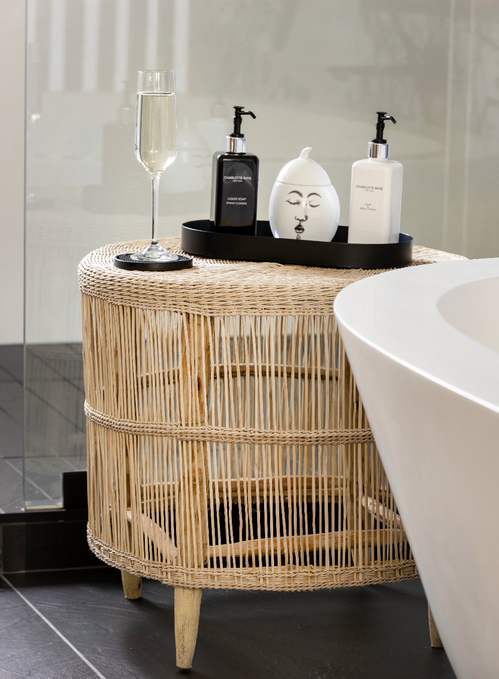 Wicker side table with bathroom items next to a bathtub