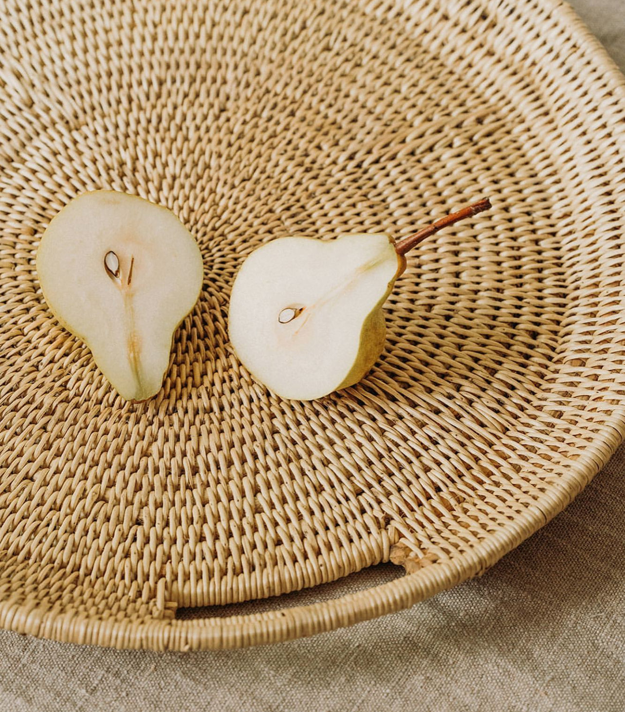Handcrafted ocean-inspired large tray with sliced pear, showcasing intricate makenge root weaving and coastal design.