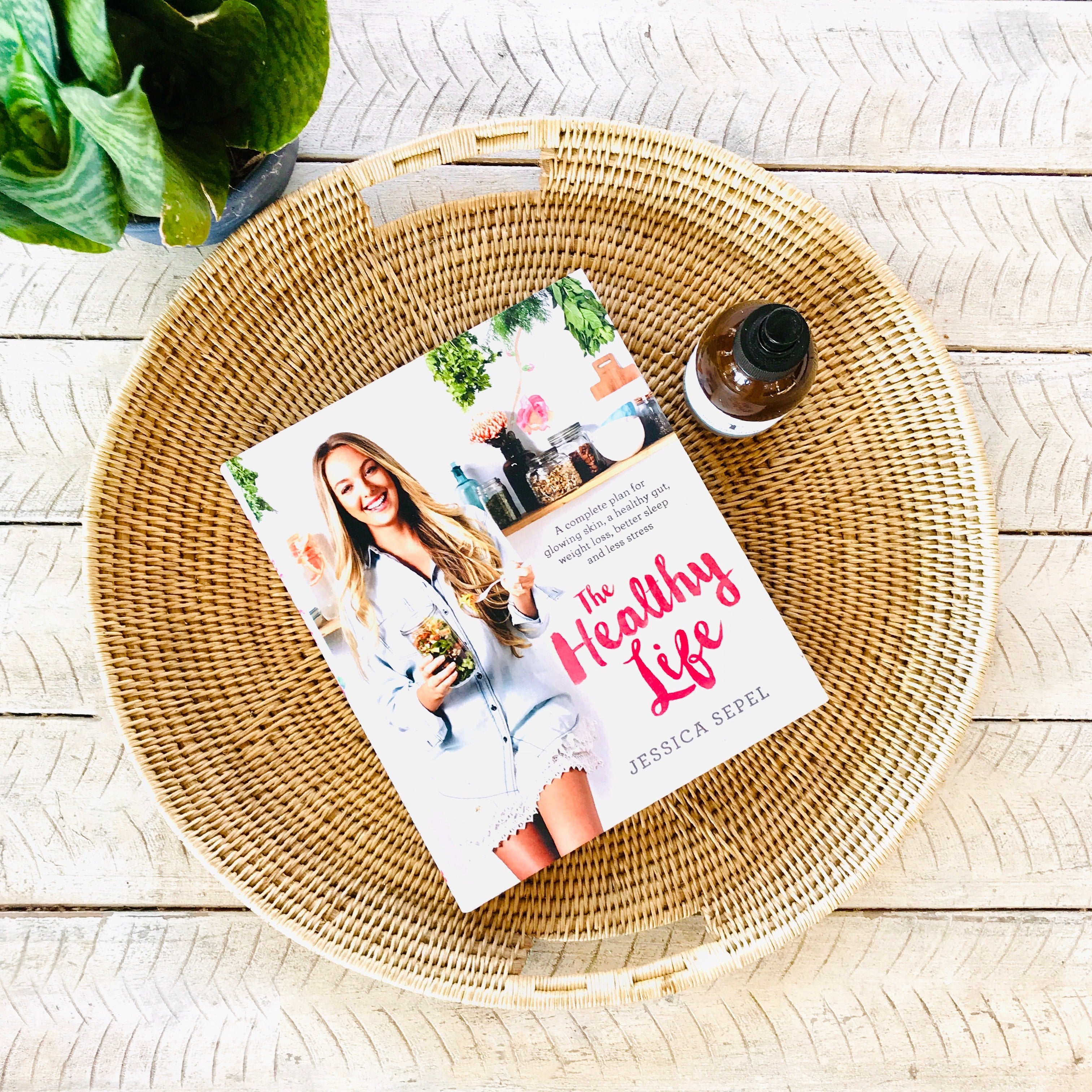Handcrafted makenge root tray with a healthy lifestyle book and essential oil on a rustic wooden surface.
