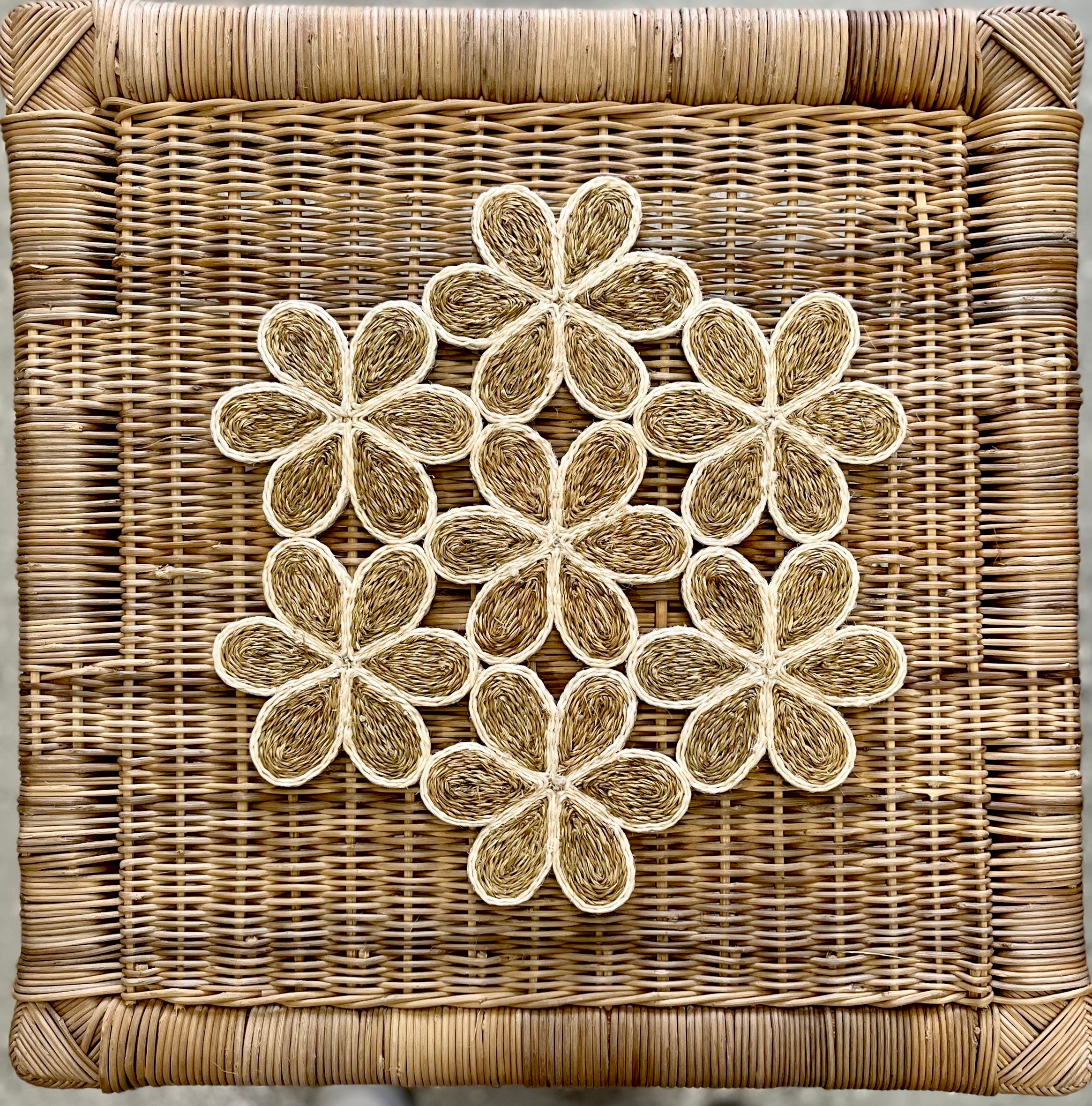 Handwoven floral-inspired placemats arranged on a natural cane background, showcasing intricate designs perfect for dining.