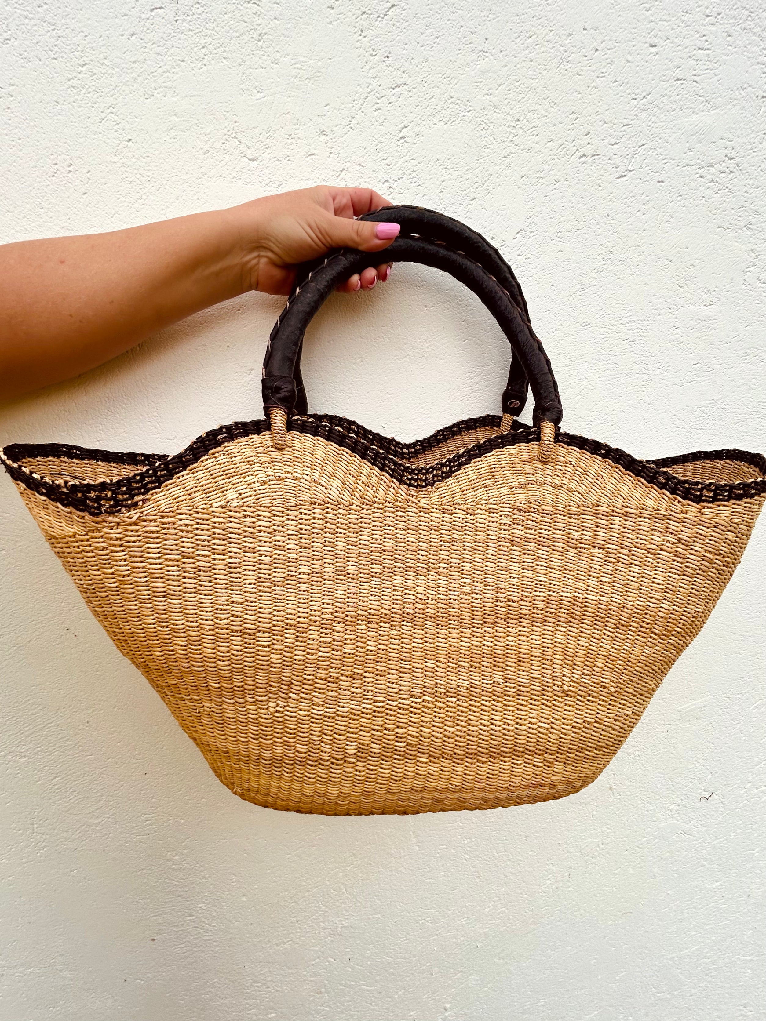 cane woven beach basket or shopping rattan basket with handles and organic curves, black leather handle with black trim