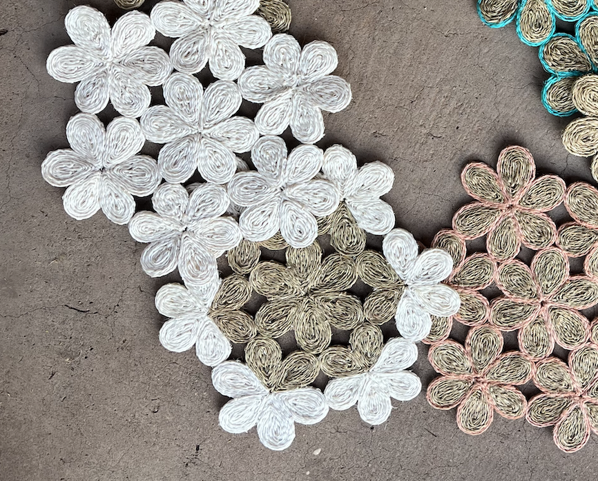 Handwoven floral inspired placemats in white, light brown, and pink, perfect for dining tables and beach picnics.