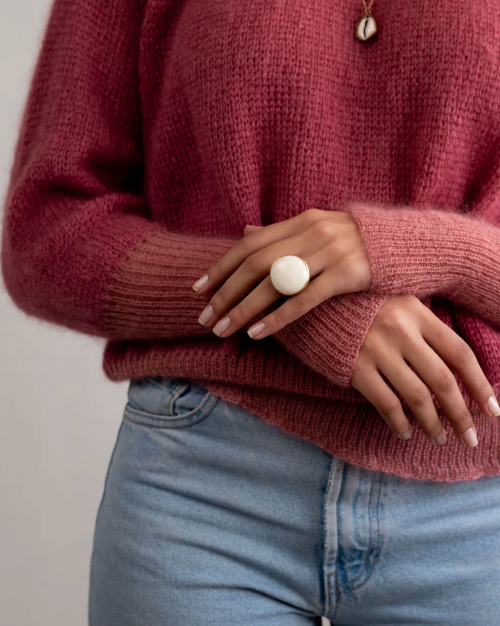 Person wearing a maroon sweater and light blue jeans with a neutral background