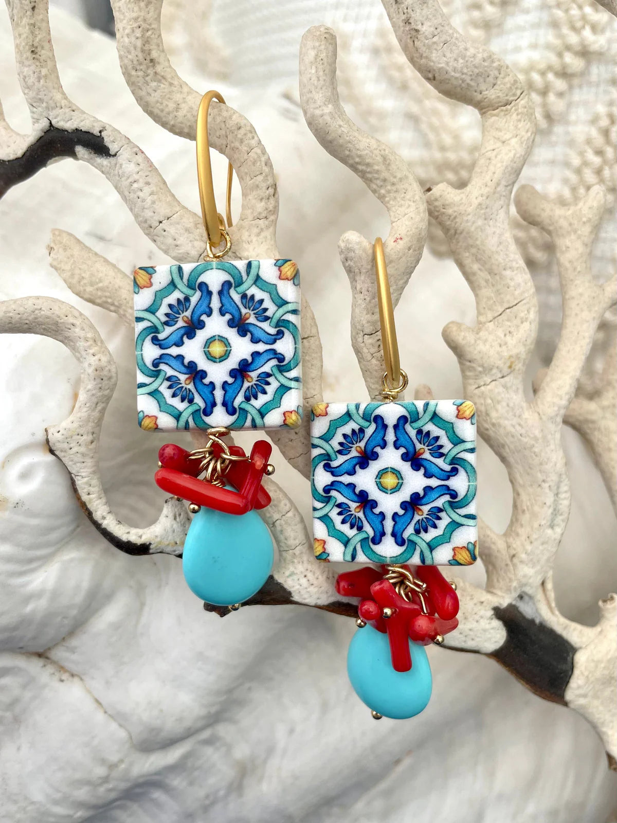 Handcrafted ocean inspired Del Vento earrings featuring turquoise drops and coral charms on gold plated brass hooks.