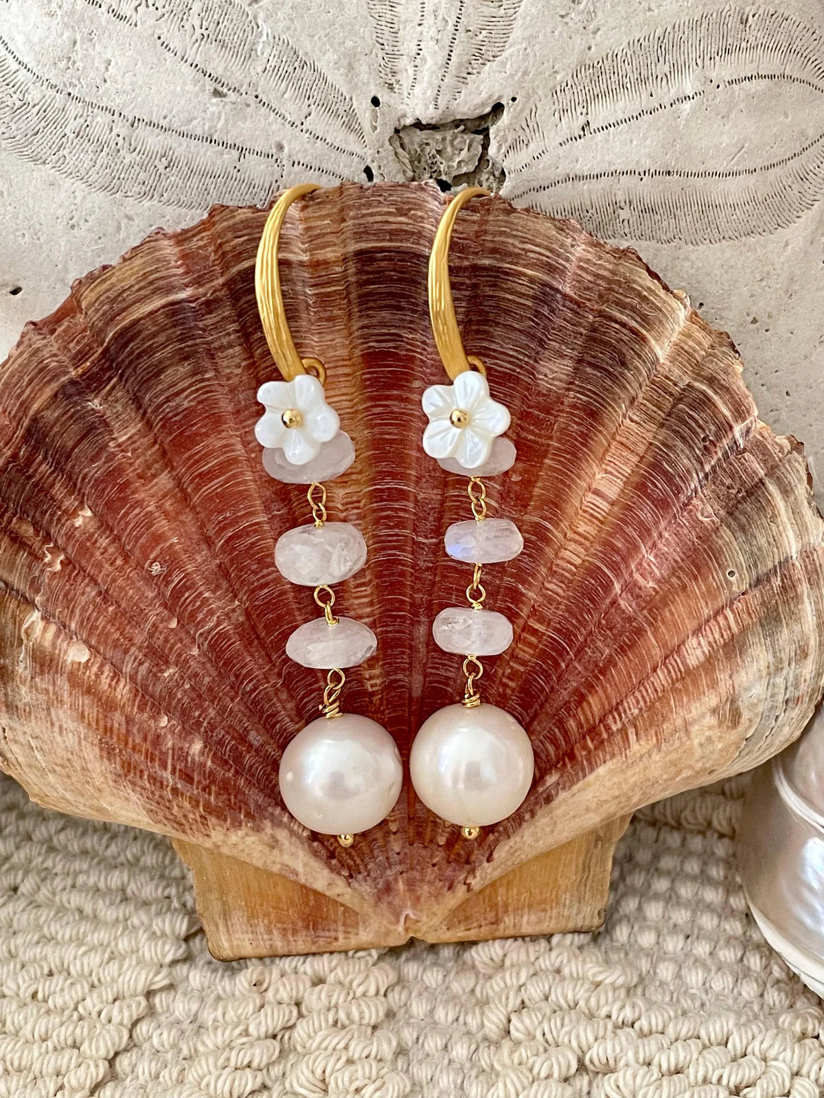 Handcrafted Gabriella Earrings featuring unique baroque pearls and mother of pearl flowers on an ocean-inspired shell backdrop.
