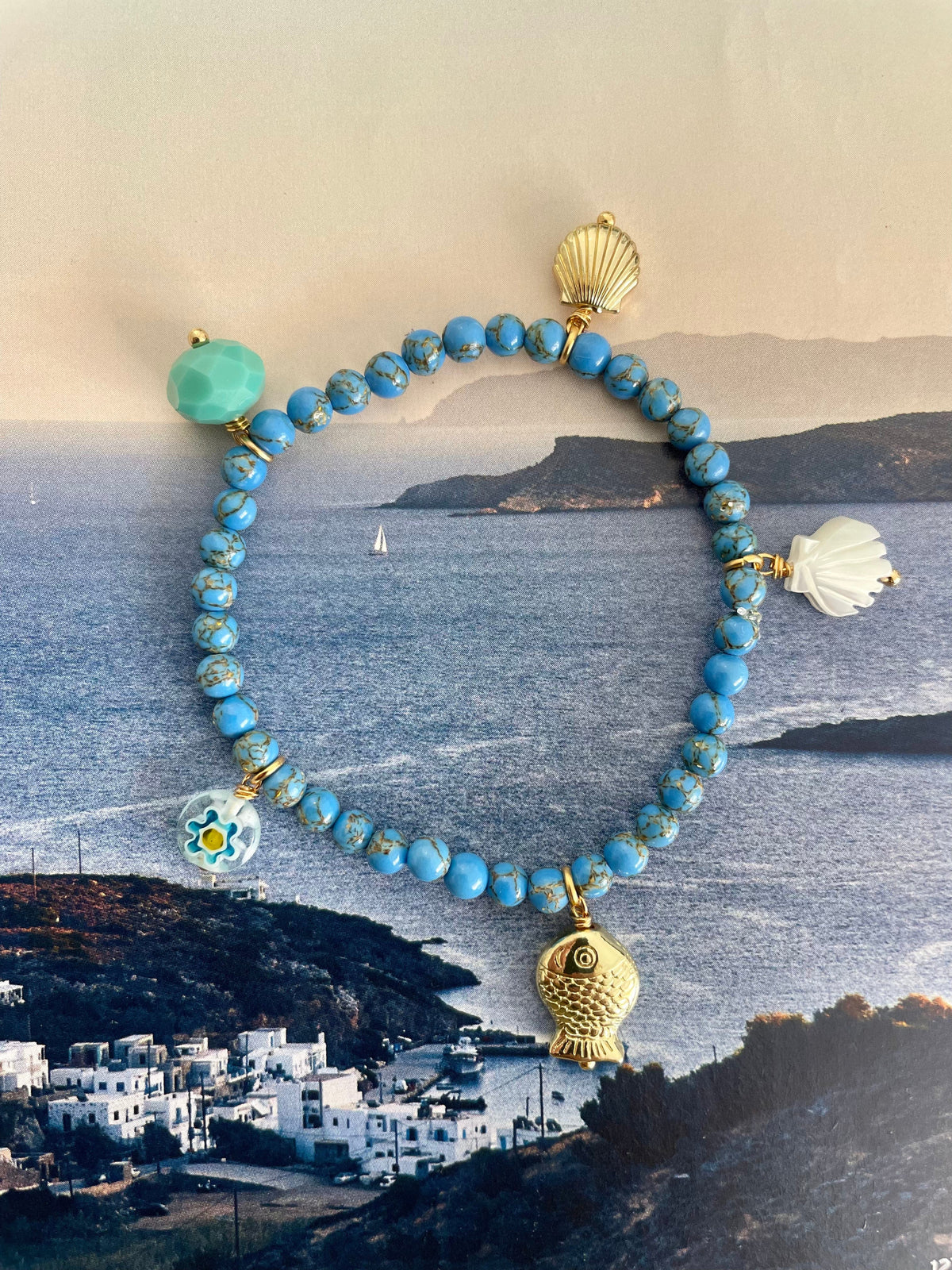 Handcrafted ocean inspired bracelet featuring turquoise beads and sea-themed charms against a coastal backdrop.