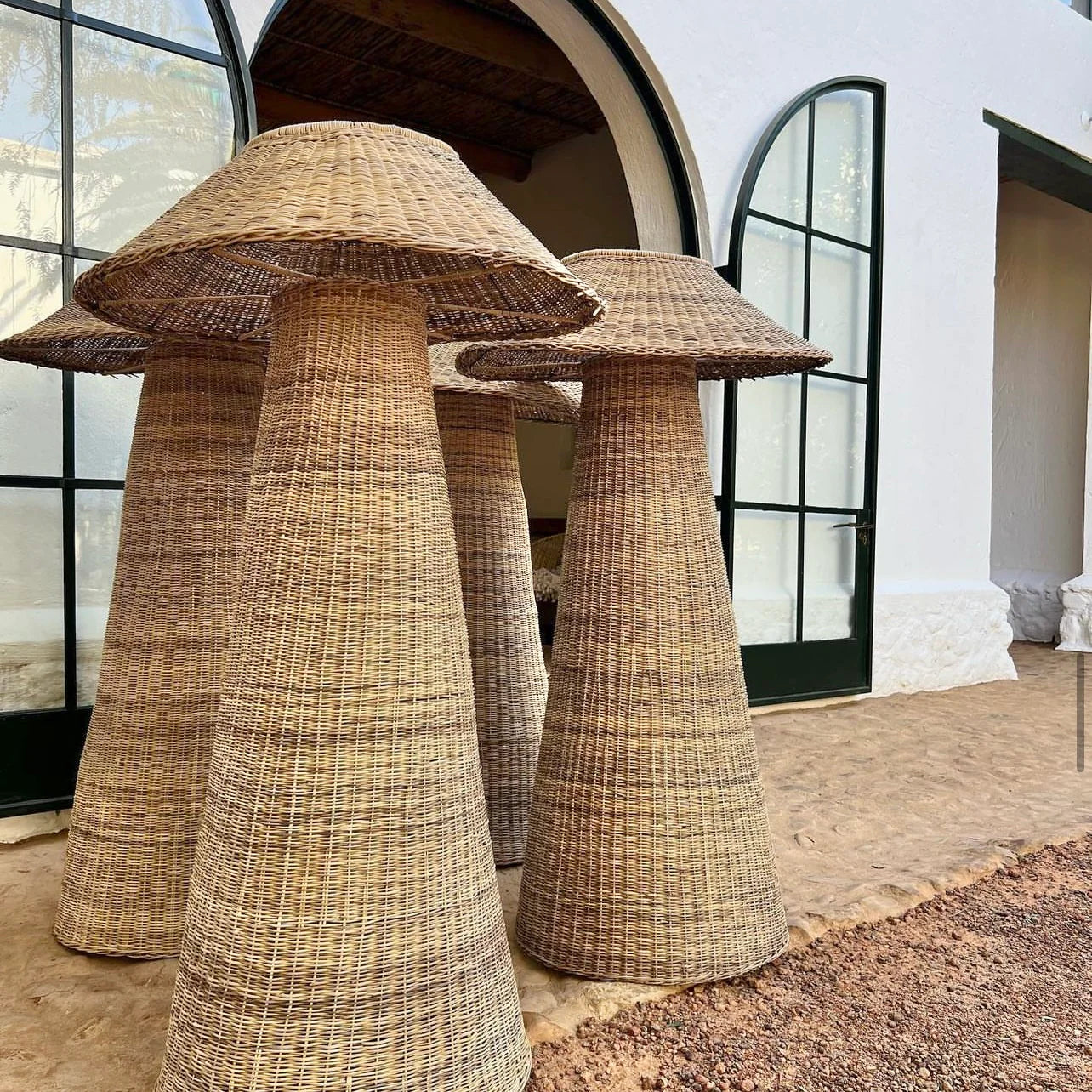 Intaba Cane Woven Floor Lamps displayed outdoors, showcasing intricate handwoven design and natural materials.