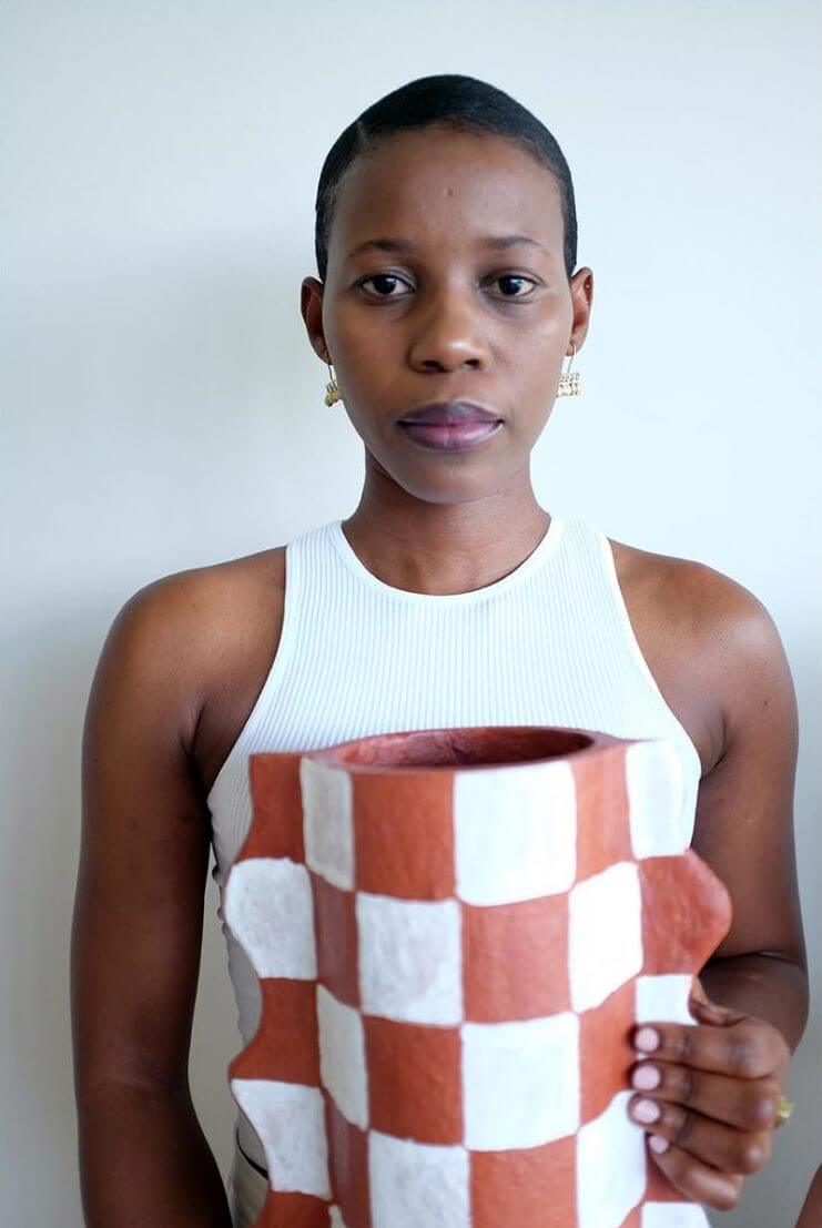 Woman holding a handcrafted terracotta checked Mude Vase, showcasing its unique design and organic shape.