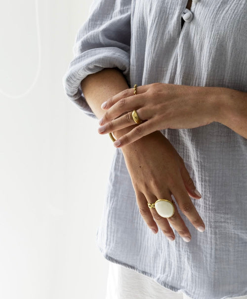 Close-up of a person wearing gold rings on a light background