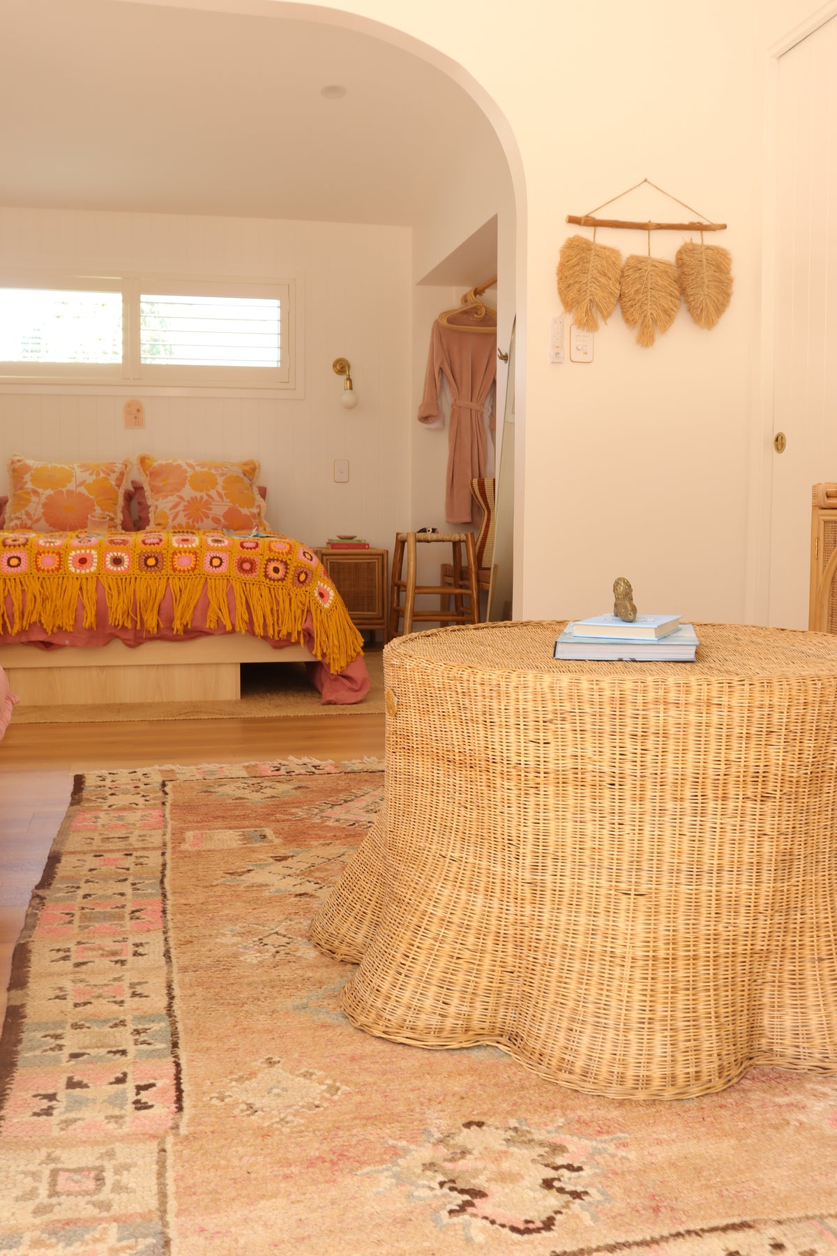Wicker chair in a room with patterned walls and a window.
