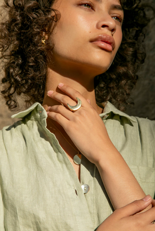 Woman wearing a green shirt with a ring on her finger, sunlit outdoors