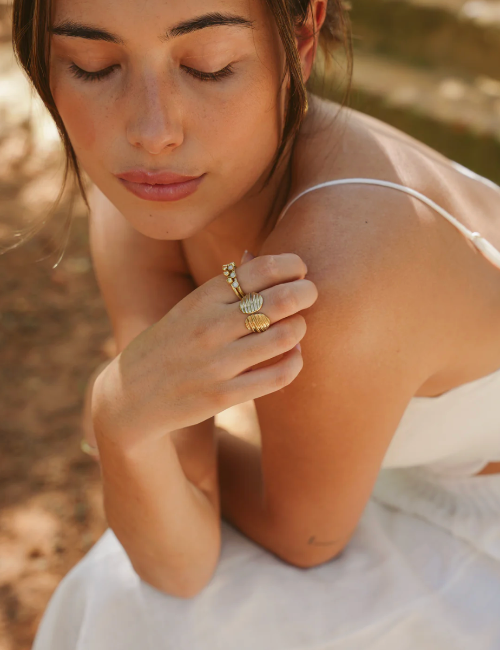 Woman wearing gold rings on a blurred natural background