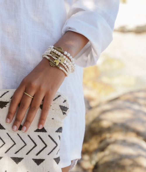Close-up of a hand wearing multiple bracelets on a blurred natural background