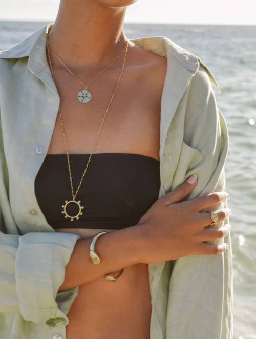 Person wearing a necklace with a pendant by the water