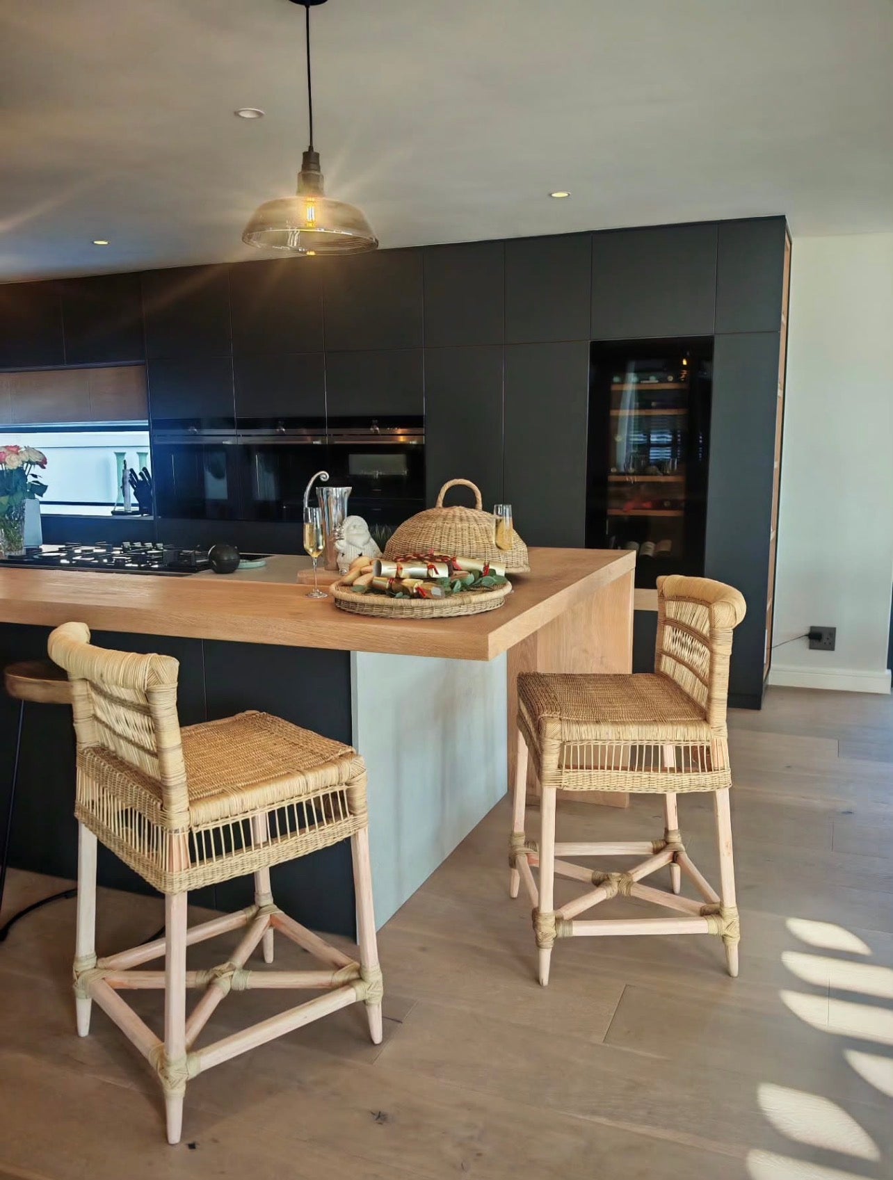 Modern kitchen with wooden counter and wicker bar stools.